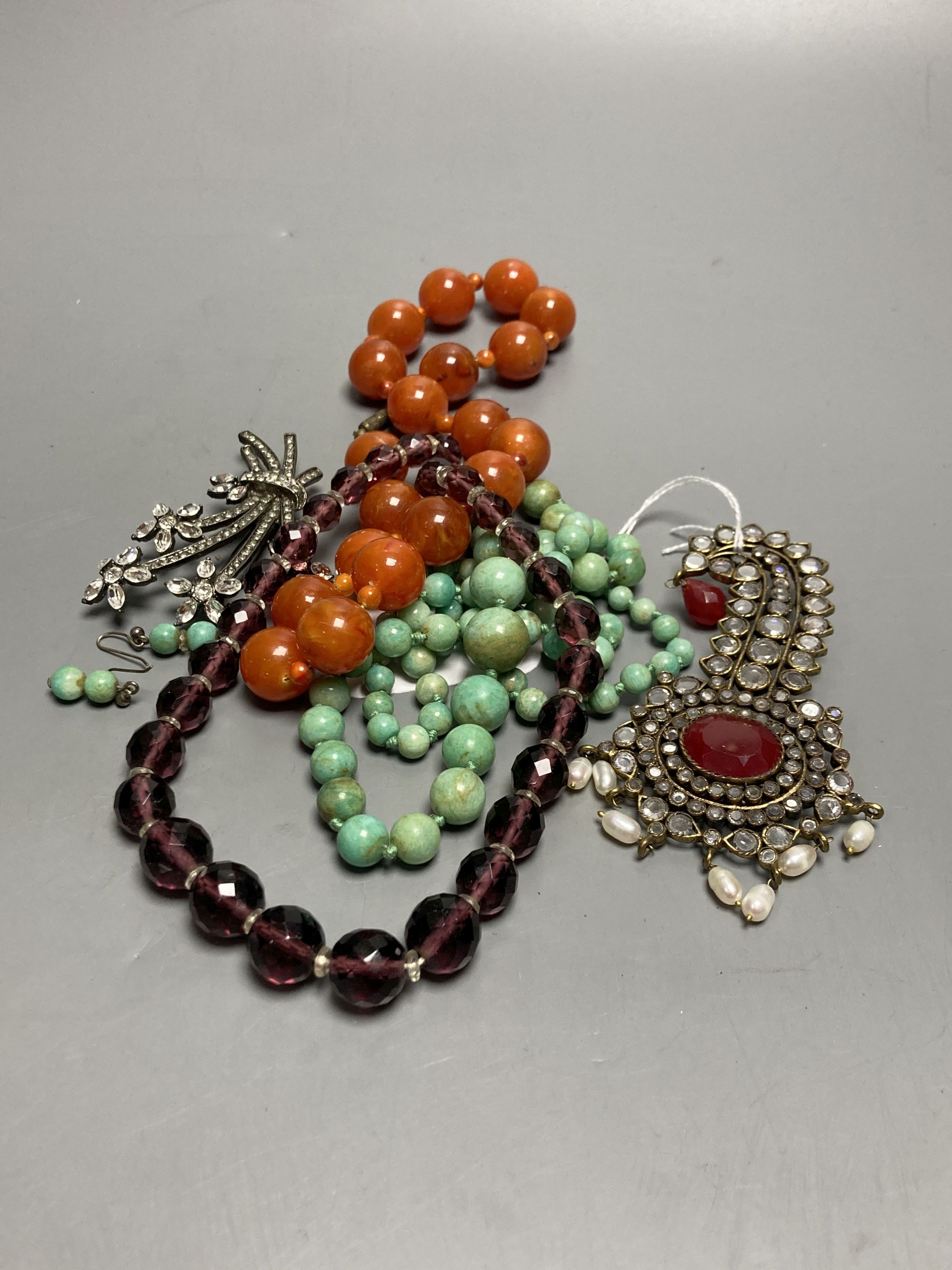 A turquoise bead necklace and pair of earrings, two other necklaces and two brooches including Indian? paste set.